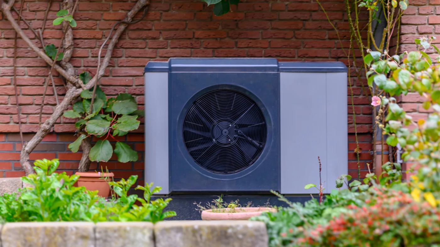 Dark blue heat pump outside brick building in Oakdale, MN