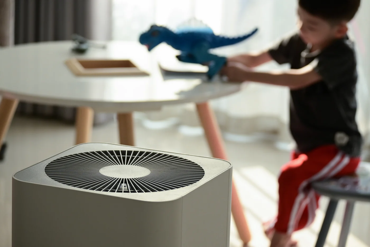 Air purifier in foreground with child playing at a table in the background