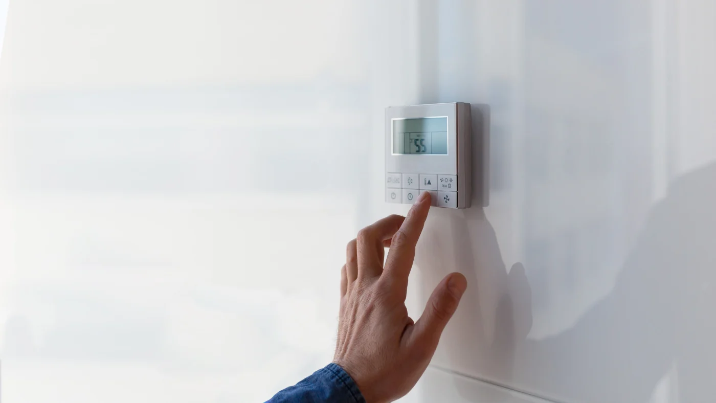 Man’s hand adjusting thermostat