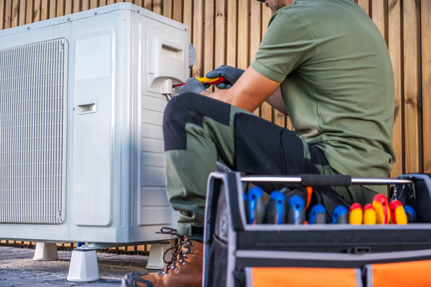 HVAC tech performing maintenance on an outdoor air conditioning unit