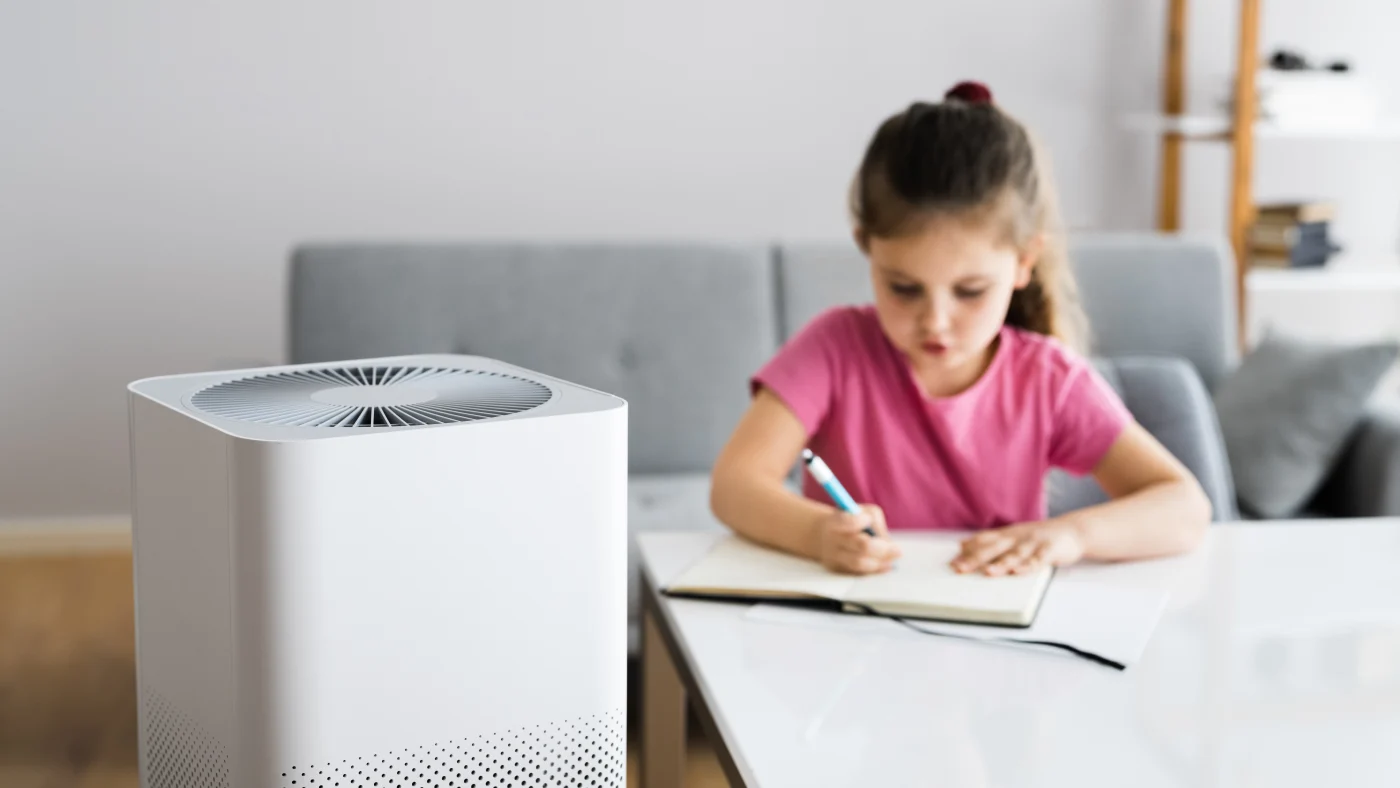 Young girl drawing at table in background with air purifier in foreground