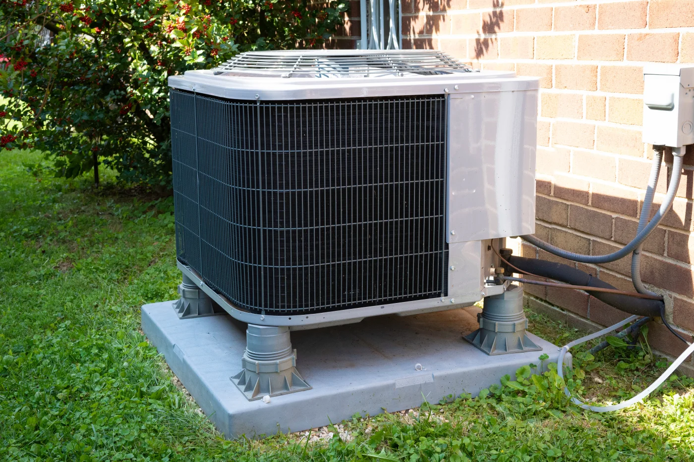 Air conditioning unit on a cement stand outside of a house