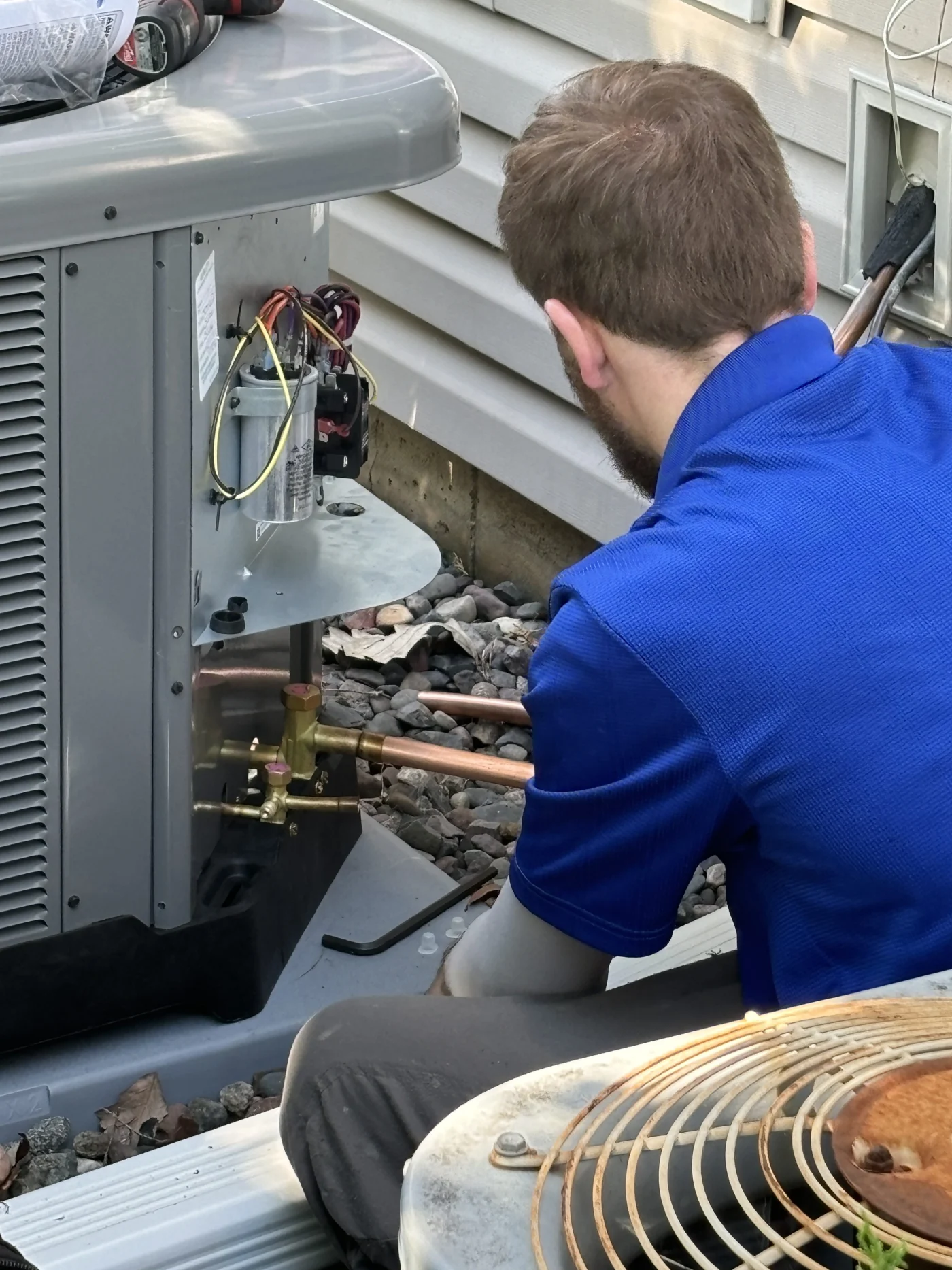 This image features an AC technician inspecting the air conditioning unit.