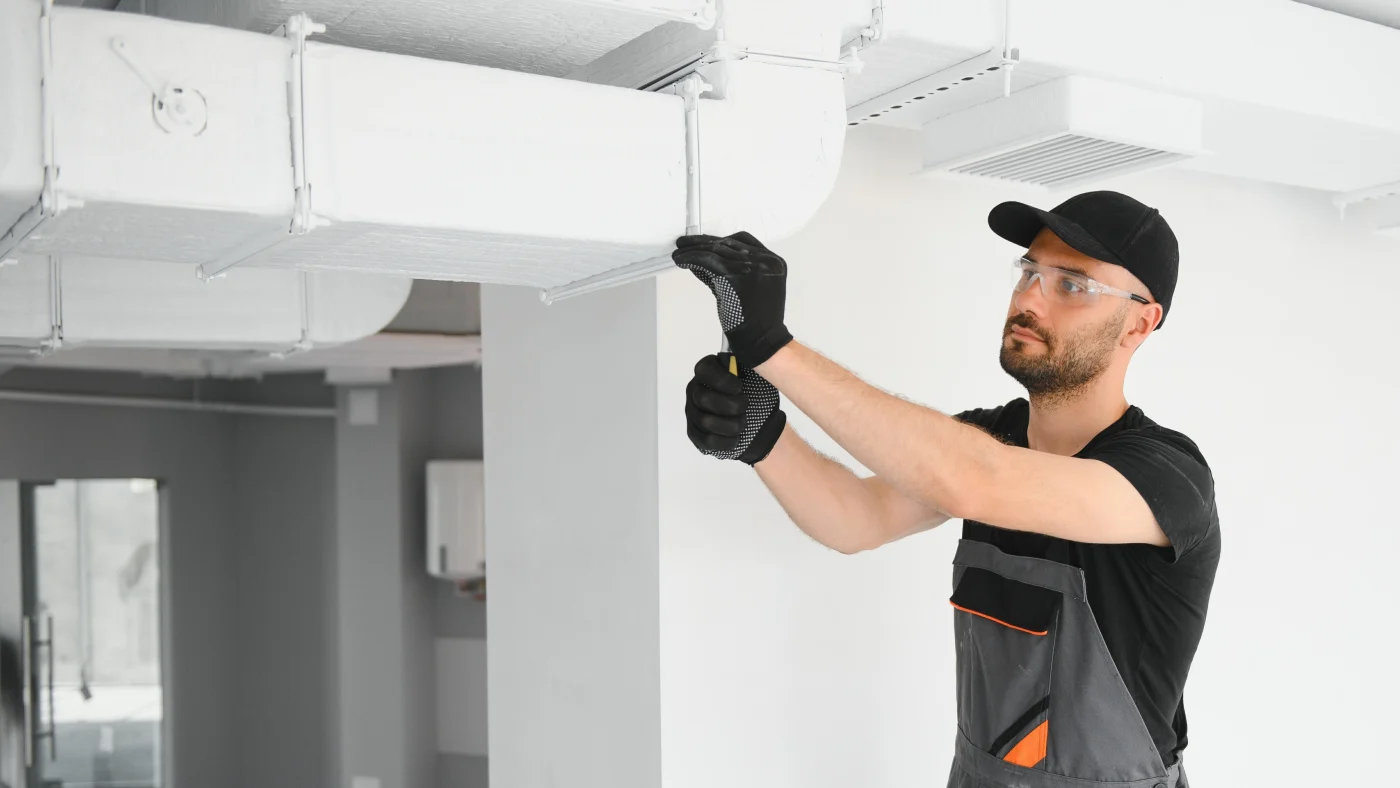 Technician working on ductwork for heating system in residence