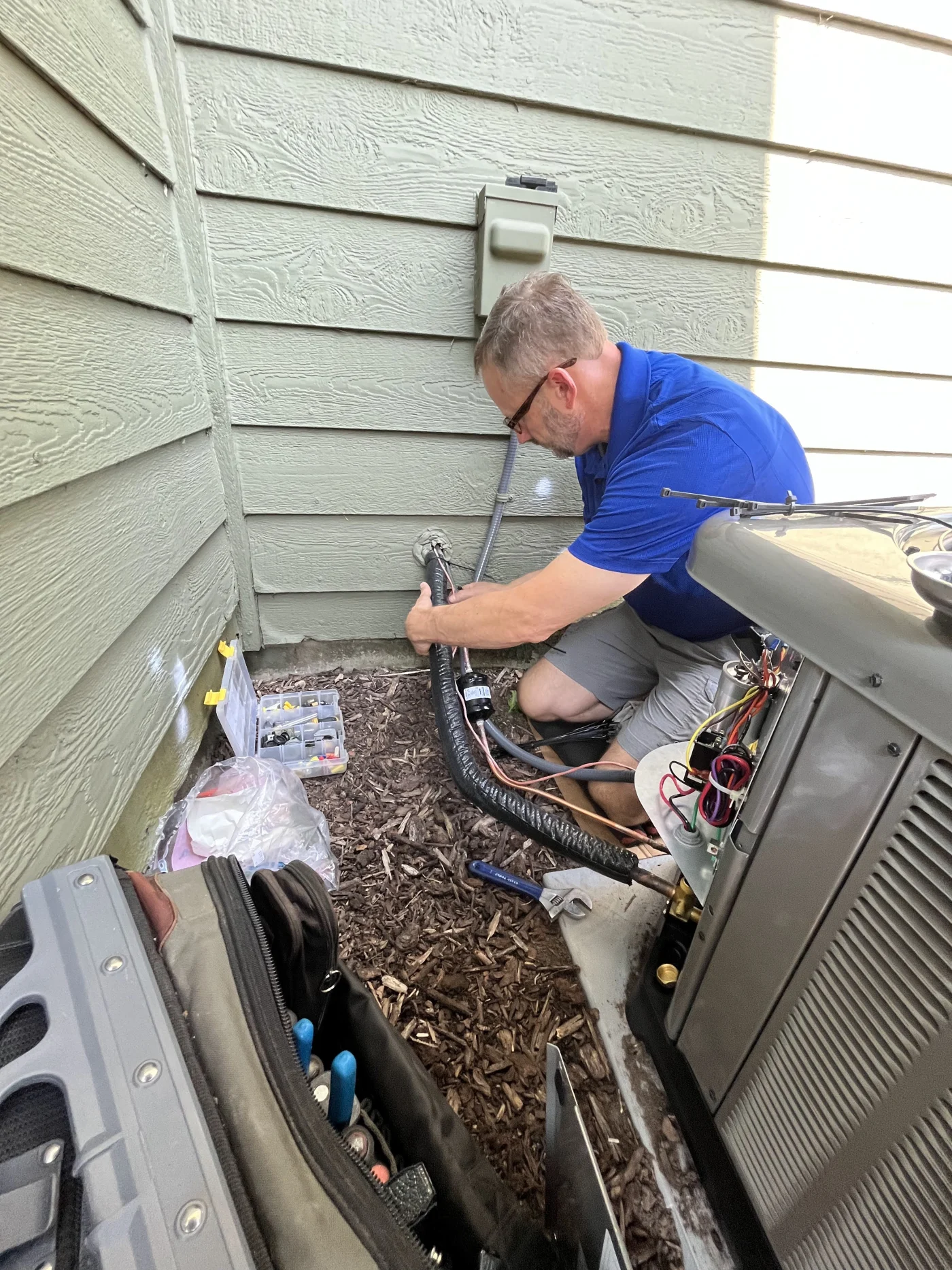 This image features a professional AC technician in uniform working on AC repairs.