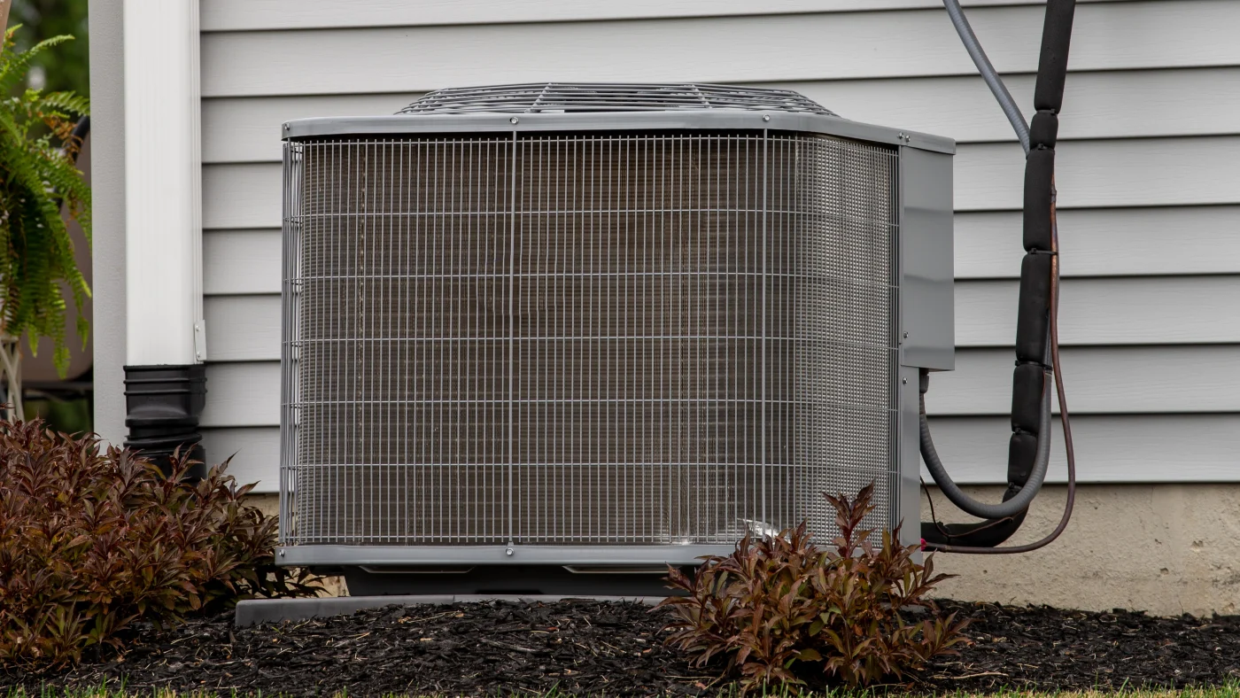 Close-up of an old AC unit outside of a home with white siding