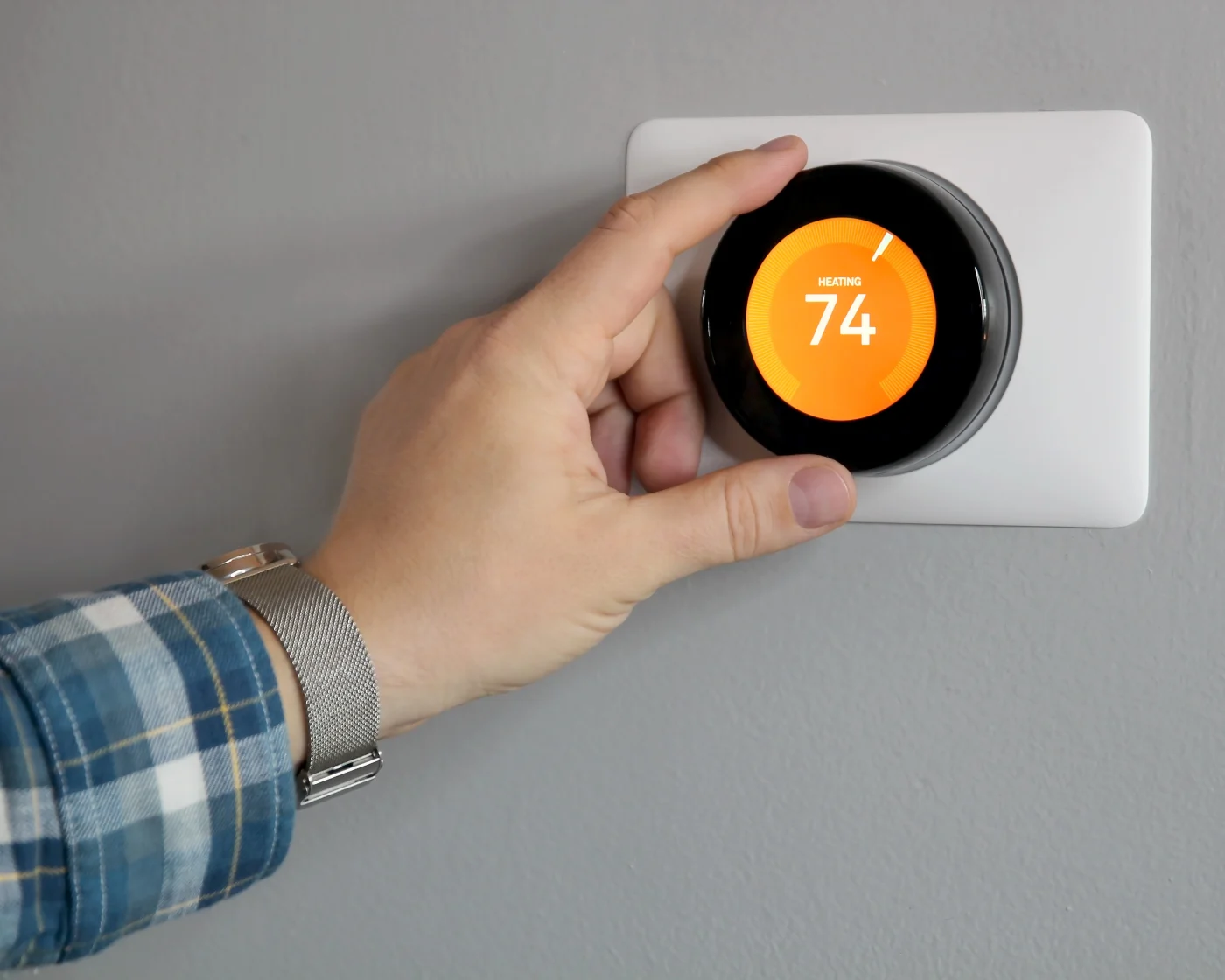 Man’s hand adjusting thermostat that reads 74 degrees