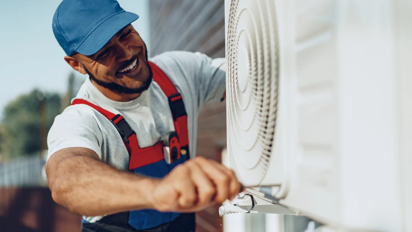 Smiling repairman servicing a/c unit