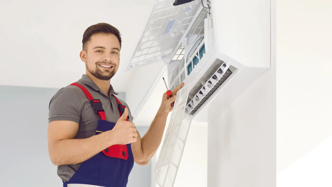 Smiling A/C repairman fixing air conditioning