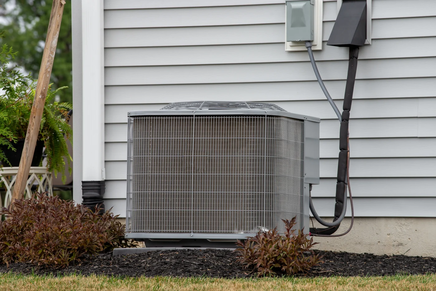 A central AC outdoor unit next to a gray siding home.