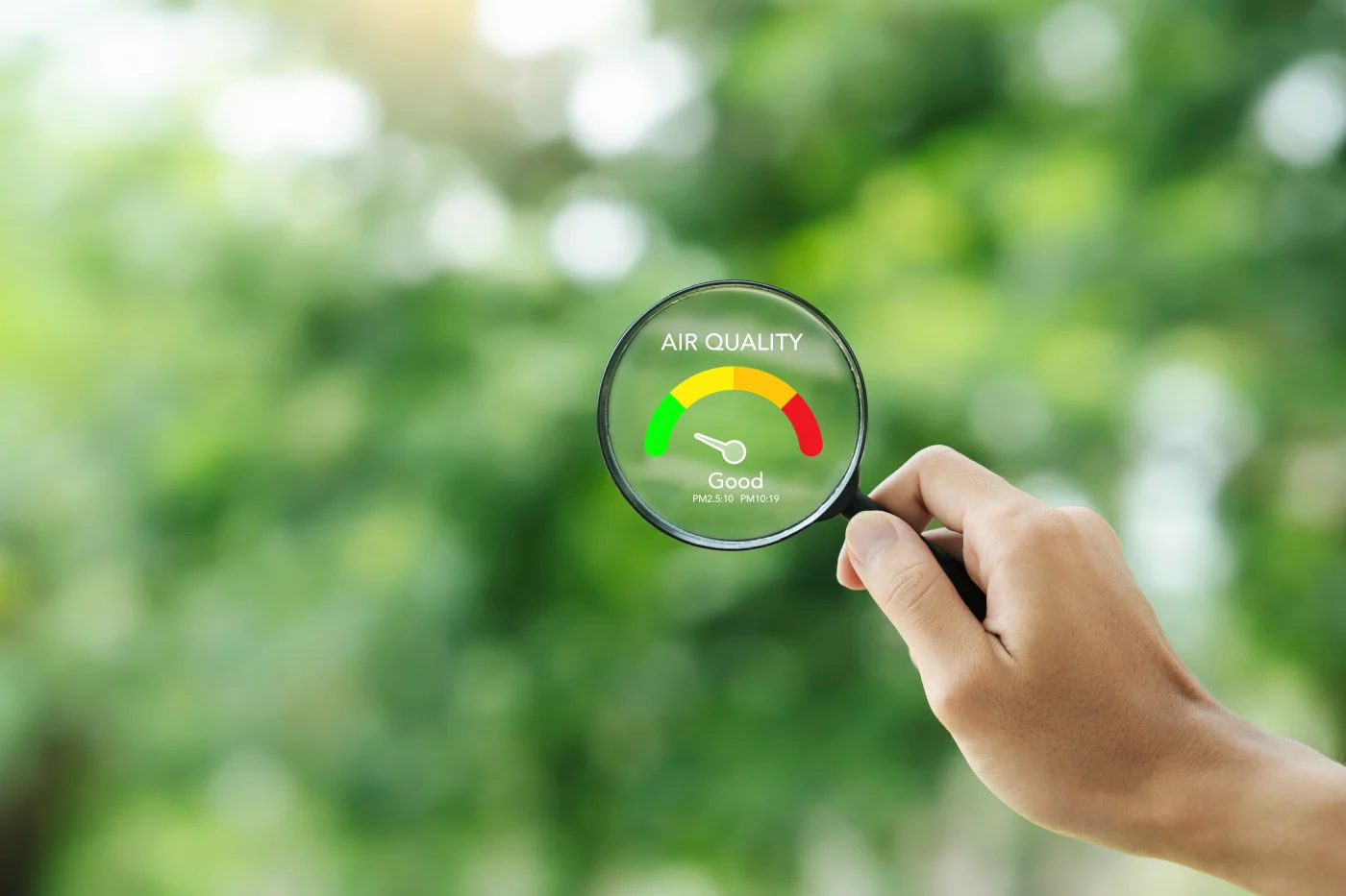 A person holds a magnifying glass over an air quality gauge.