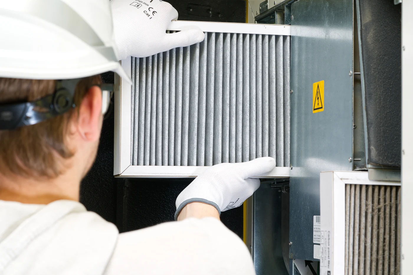 An HVAC technician replaces a filter on a furnace