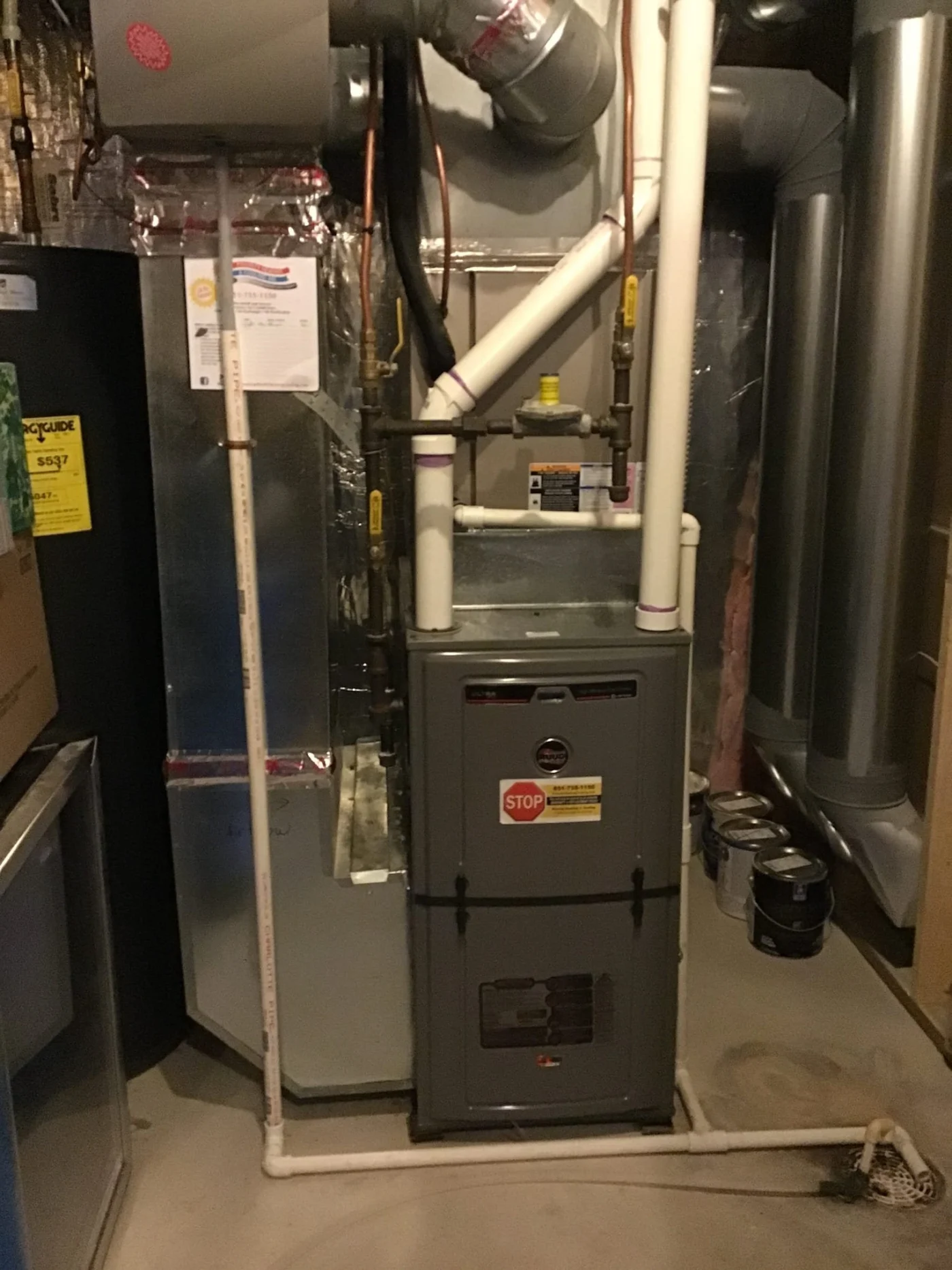 Dependable Furnace Service | Cottage Grove, MN A residential basement mechanical room showing a gray gas furnace connected to PVC venting, copper gas lines, and metal ductwork, with drainage piping.