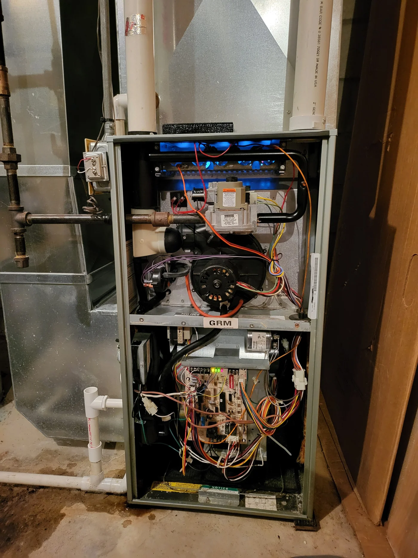 Dependable Furnace Service | Inver Grove, MN Open residential furnace cabinet showing internal burners, blower motor, wiring, control board, and PVC venting during a service inspection.