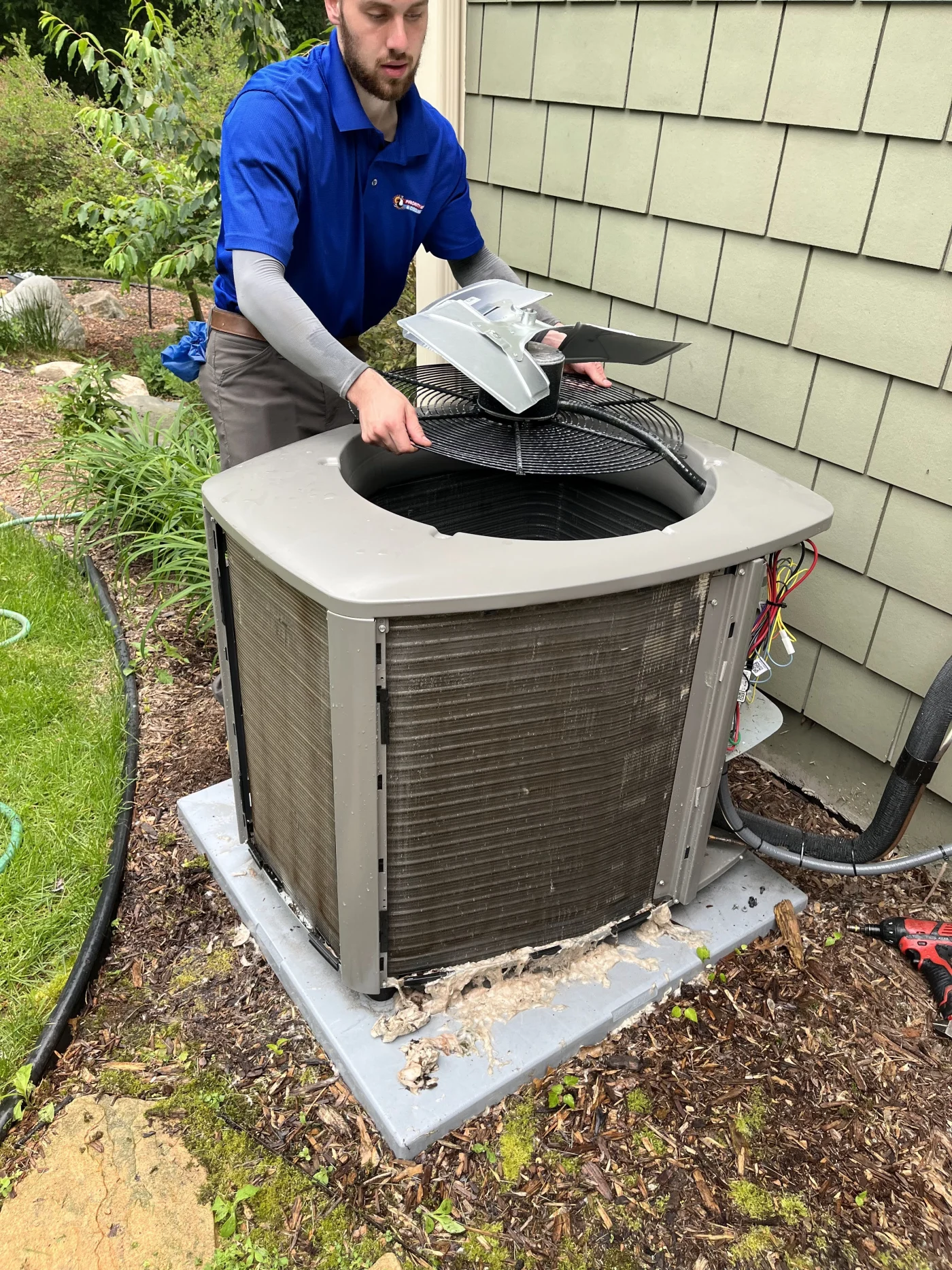 Dependable AC Service | Maplewood, MN | Priority Heating and Cooling An HVAC technician in a blue shirt is lifting the fan assembly from an outdoor air conditioner condenser while servicing the unit.